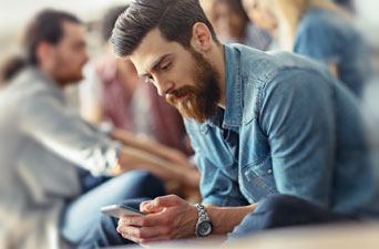 A handsome man with a long beard browsing on his phone