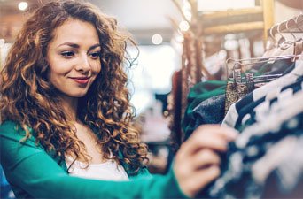 A beautiful young lady with a curly hair selecting clothes from dresser