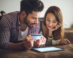 A sweet couple holding coffee in his hand looking at the tablet 