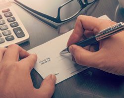 Close up of hands writing a check.