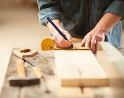 Hands measuring some wood before a cut.